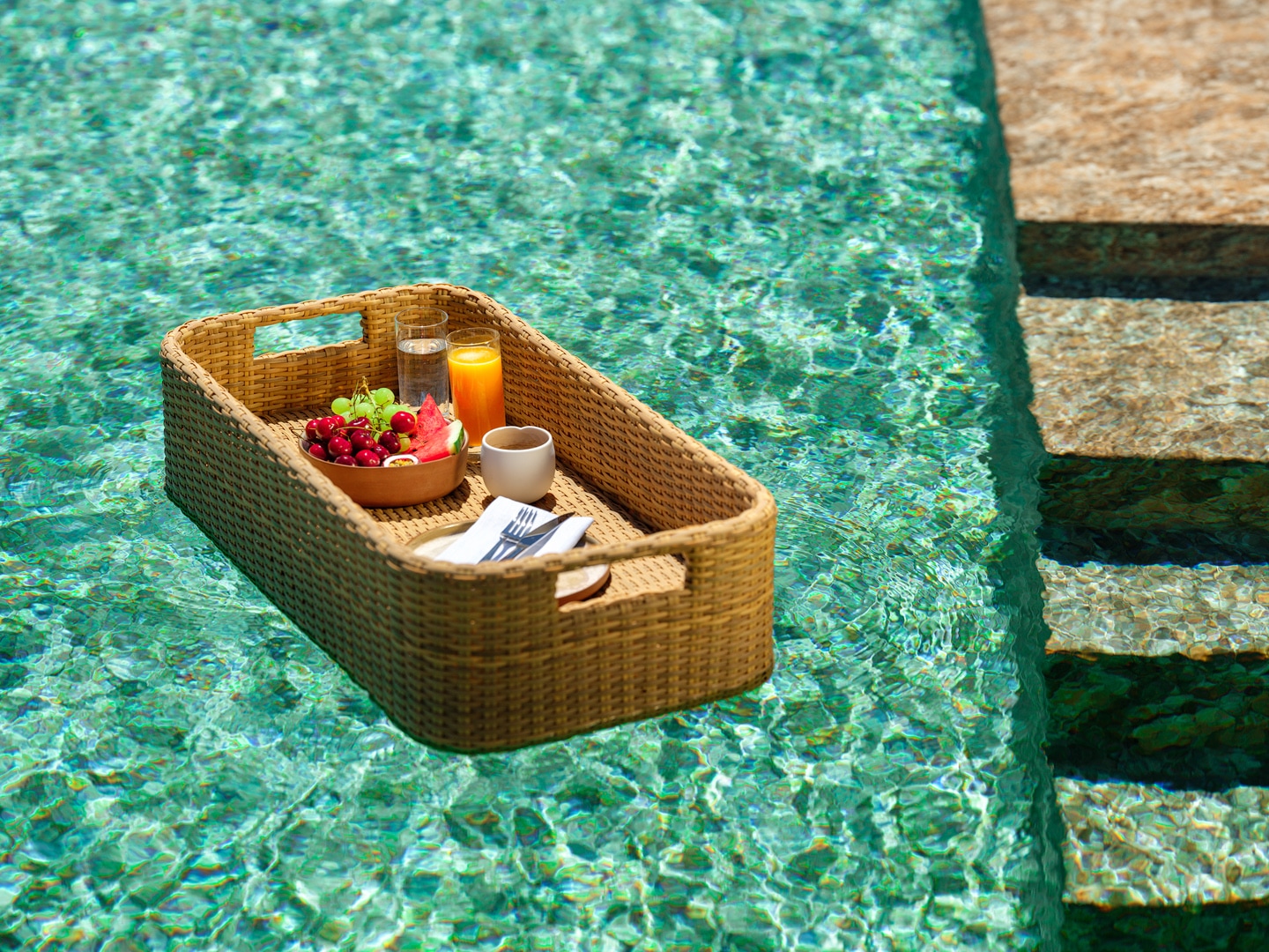 Floating breakfast tray with fresh fruits, juice, and coffee in the salt-water pool at Patmosphere Luxury Escape, Greece