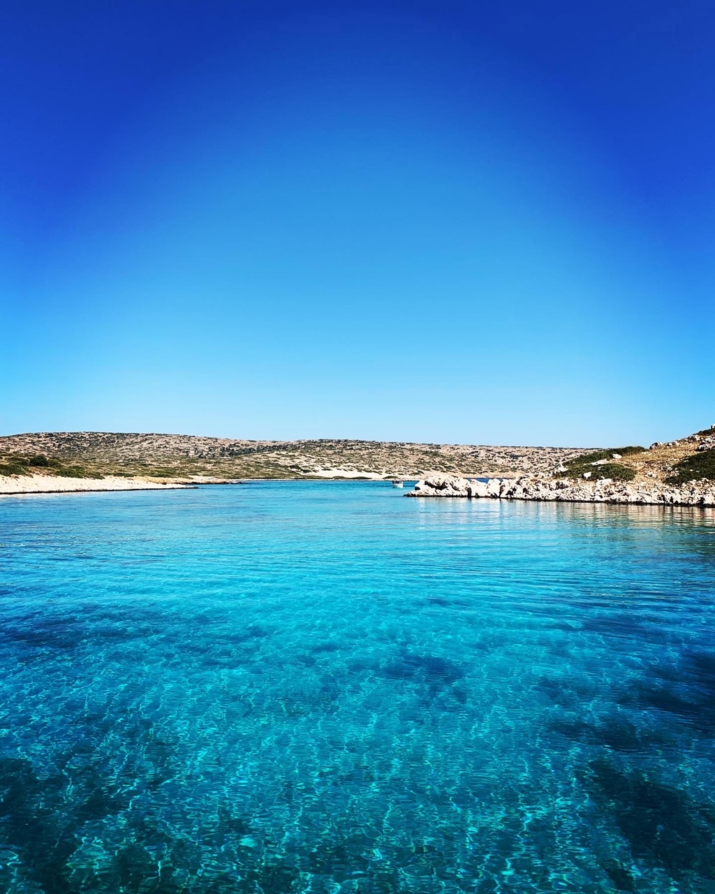 Turquoise blue lagoon surrounded by rocky coast near Patmos island