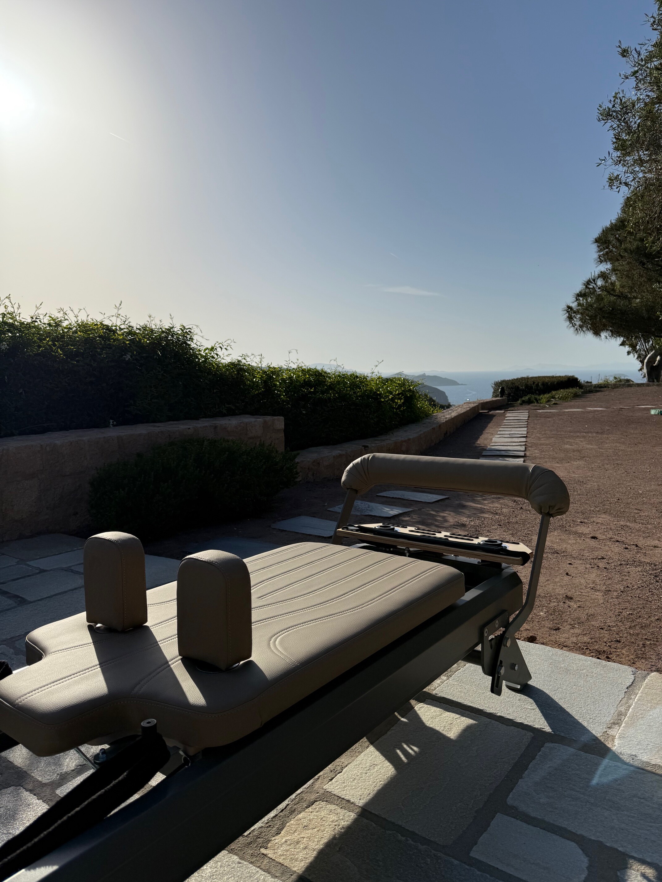 Sunlit Pilates reformer on terrace overlooking Patmos greenery 